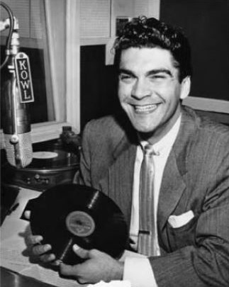 Chico Sesma smiles with record in hand at the KOWL microphone.